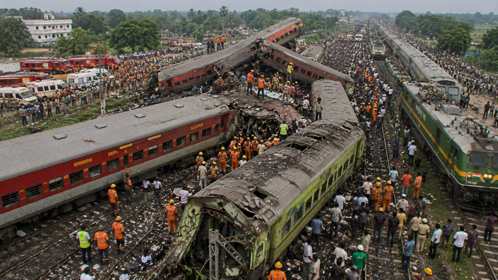 2023 की बालासोर रेल दुर्घटना (ओडिशा) का यथार्थवादी चित्र, जिसमें कोरोमंडल एक्सप्रेस, यशवंतपुर–हावड़ा एक्सप्रेस और मालगाड़ी की भीषण टक्कर के बाद क्षतिग्रस्त डिब्बे, राहत एवं बचाव अभियान और दुर्घटनास्थल का दृश्य दिखाया गया है।